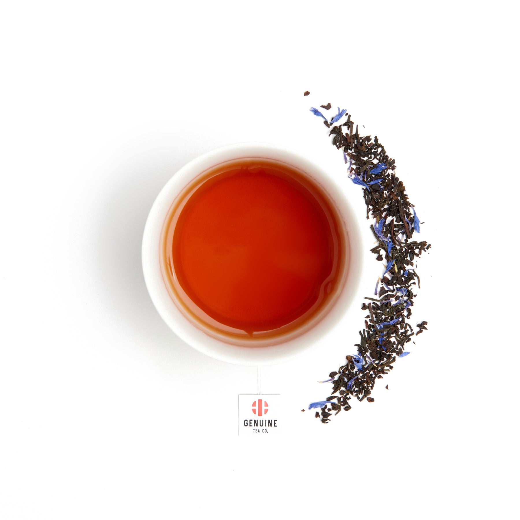 Overhead view of a cup of brewed tea, surrounded by tea leaves