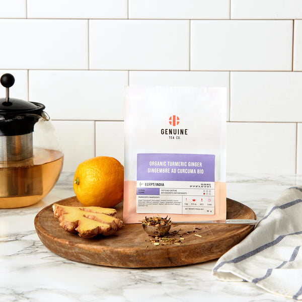bag of Organic Turmeric ginger tea on a kitchen counter, next to some ginger and an orange
