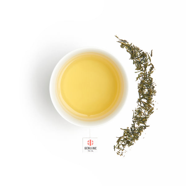 Overhead view of a brewed cup of Organic Sencha Kyoto tea, next to some tea leaves 