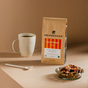 12oz bag of Guatemala, next to a mug of coffee and some pecans