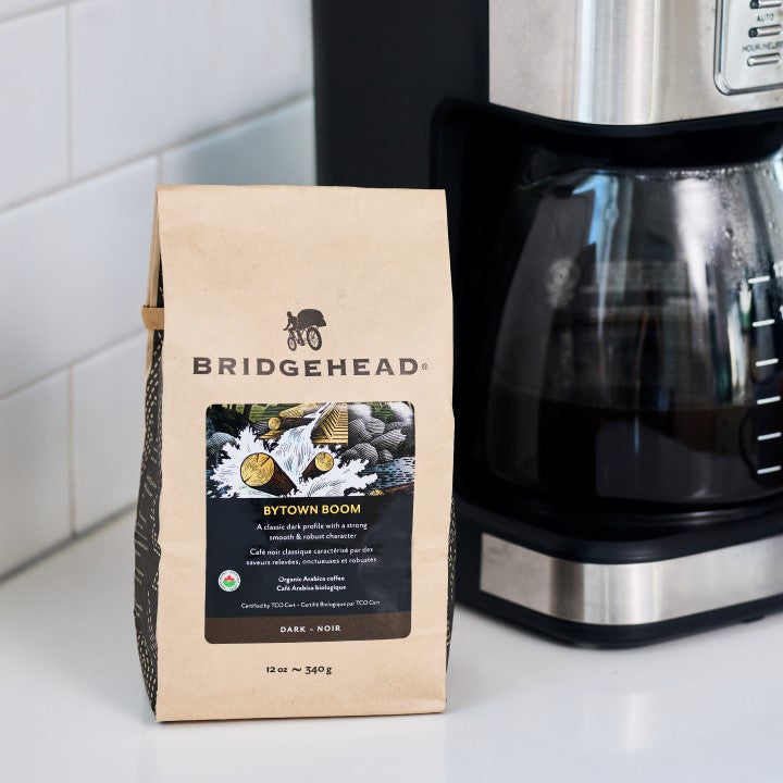 12oz kraft bag of Bytown Boom Coffee next to coffee maker